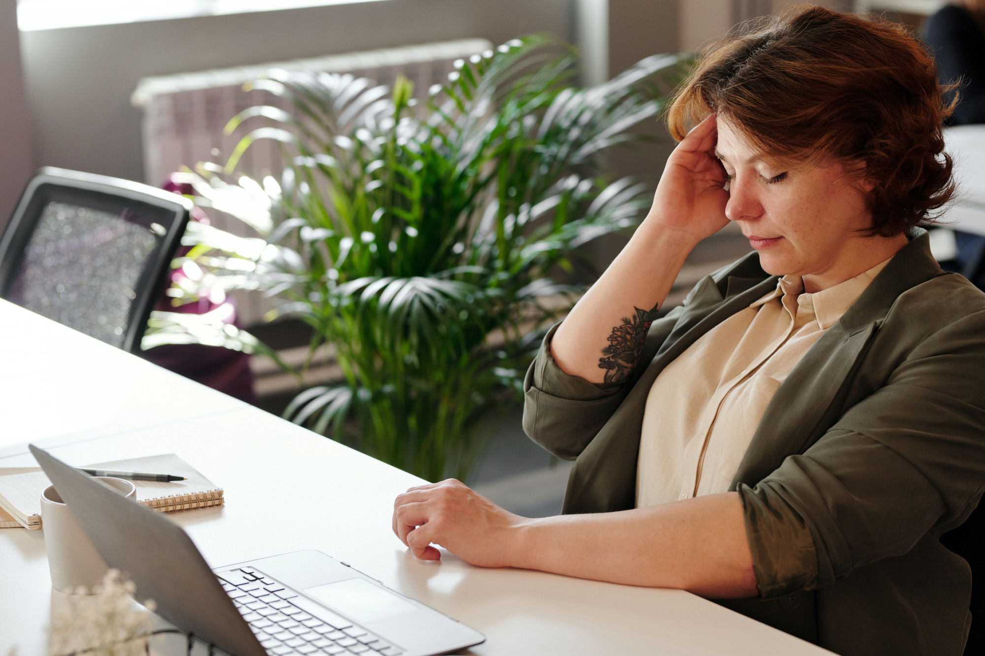 Woman sitting at desk, appearing to have a headache
